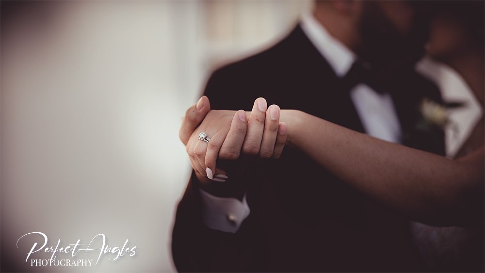 Close-up of a bride and groom holding hands